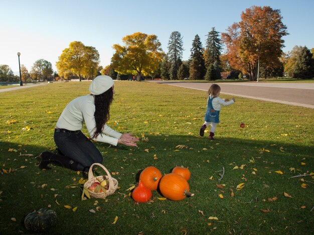 秋の公園で母親と一緒に幼児の女の子。