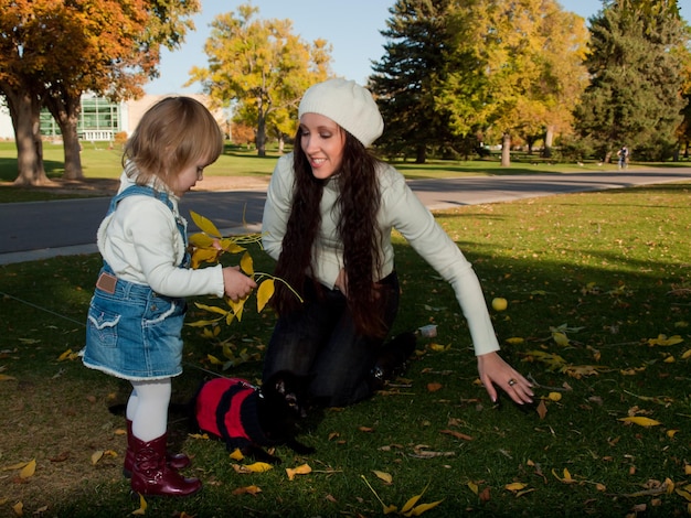 Girl toddler with her mother in autumn park.