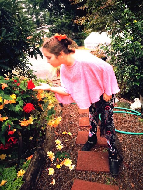 Photo girl touching flower while standing in yard