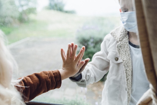 Foto ragazza che tocca il vetro mentre guarda un ragazzo in piedi all'aperto