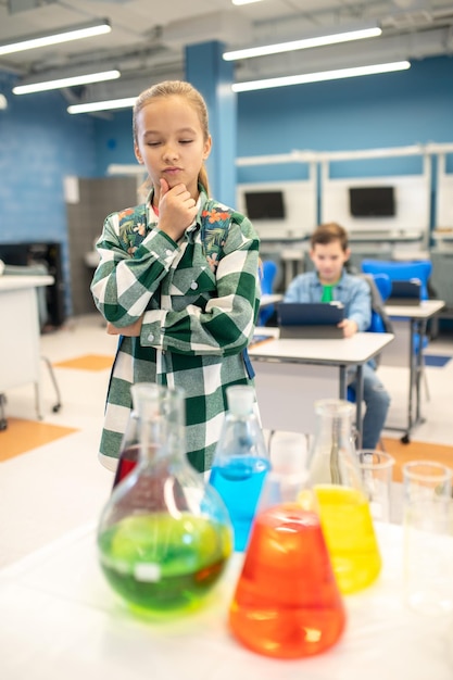 Girl touching her chin looking at flasks