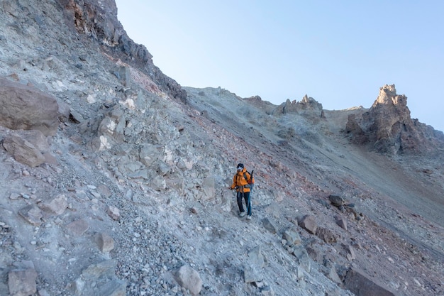 多くの単一遺伝子の噴出口と溶岩ドームに囲まれたエルギー山の大きな成層火山を登る少女観光客