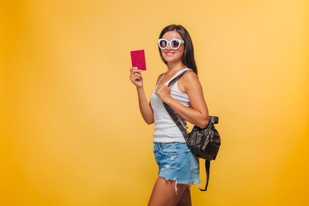 Girl tourist on a yellow background with a backpack and a passport