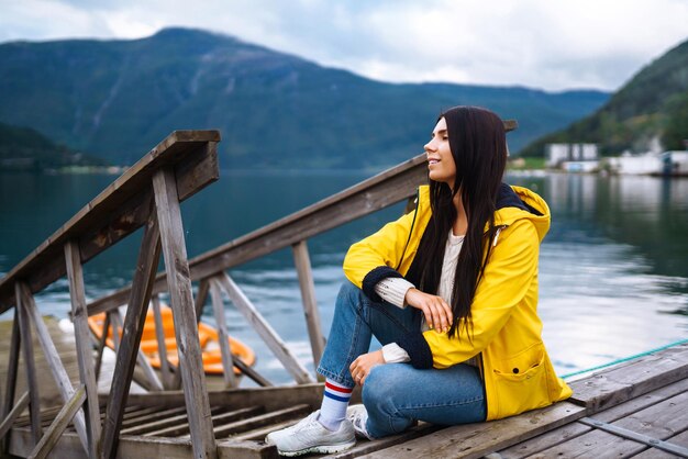 Girl tourist in yellow jacket Active woman relaxing in Norway Travelling lifestyle adventure