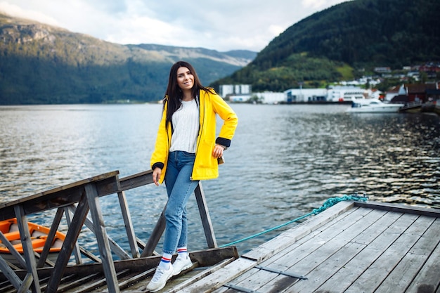 Turista della ragazza in una giacca gialla che posa sul lago in norvegia avventura di stile di vita itinerante