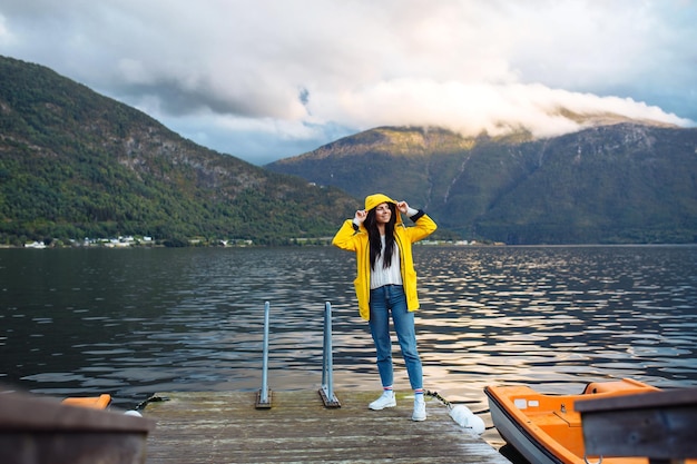 Girl tourist in a yellow jacket posing on the lake in Norway Travelling lifestyle adventure