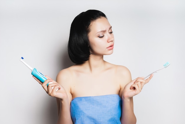 Girl in a towel holds toothbrushes in her hands