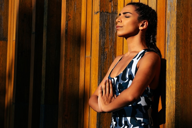 A girl in a tracksuit on a wooden background in a tight-fitting suit meditates