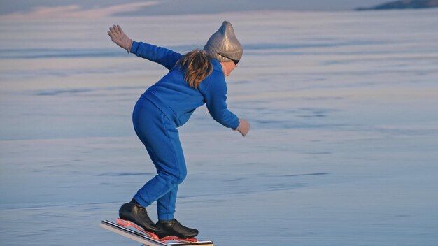 The girl train on ice speed skating. The child skates in the winter in blue sportswear suit, sport glasses. Children speed skating sport.