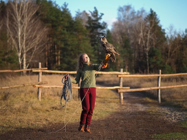 Girl trainer holds an owl on her hand.