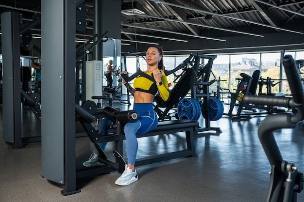 Girl training back muscles on pulldown machine in gym