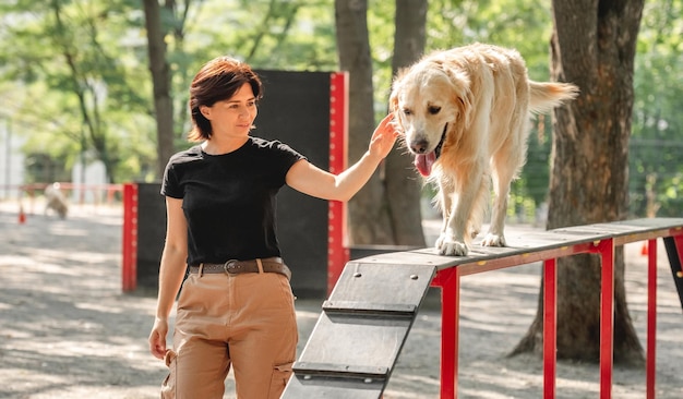 야외에서 골든 리트리버 개를 훈련시키는 소녀. 함께 공원에서 강아지 애완 동물을 가진 젊은 여자