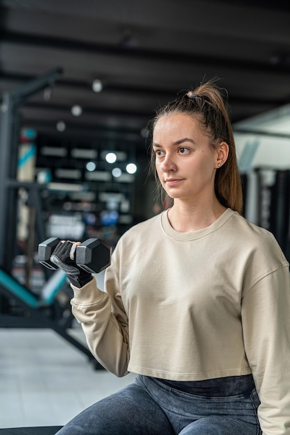 Girl in training with heavy large dumbbells trains arm endurance