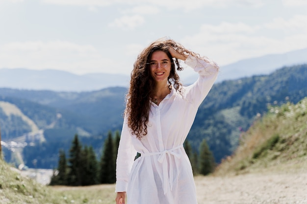 Girl traveler smiling in the mountains. Attractive woman posing on the green hills   Tourism