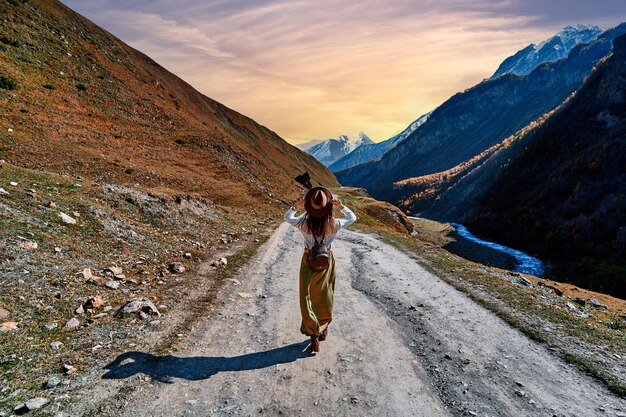 Girl traveler walks along the road in a mountain gorge