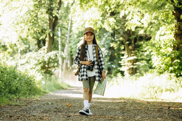 Girl traveler in woods with binocular and map