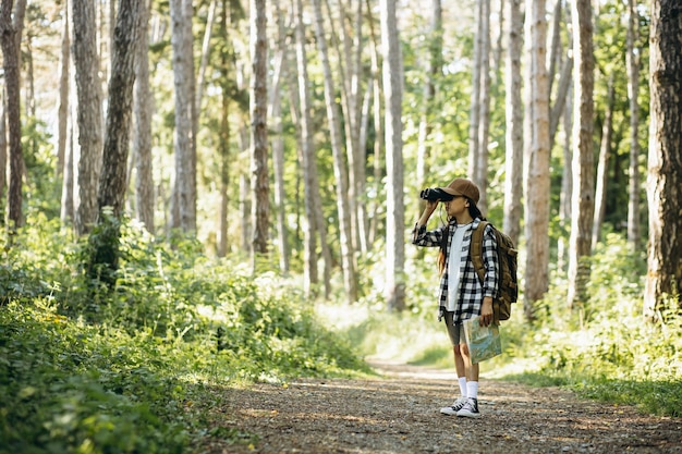 Girl traveler in woods with binocular and map