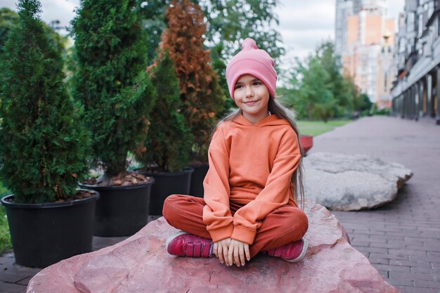 Girl in trendy hats and hoodie having fun in park fall vibes autumn beauty style child fashion