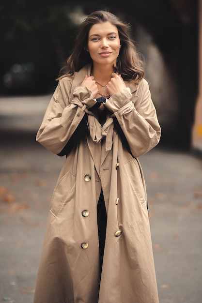 A girl in a trendy trench coat walks in the old town