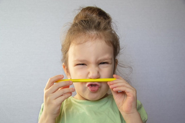 The girl tries to hold the pencil with her upper lip and nose\
speech therapy exercise speech