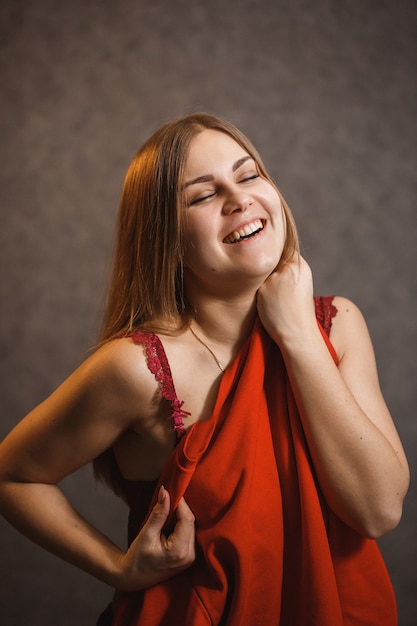 Girl tries on a red sweater on a gray background