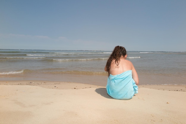 Ragazza su una spiaggia tropicale con asciugamano verde