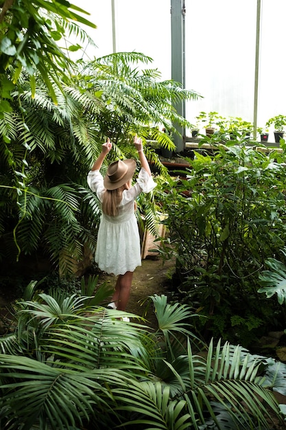 Girl among tropical plants turned her back to the window