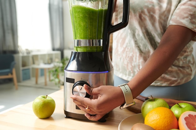 Girl turning on blender to make smoothie