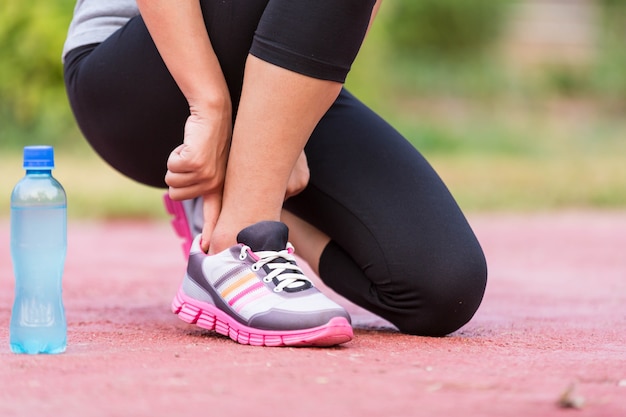 Girl tying jogging shoes. A person running outdoors on a sunny day