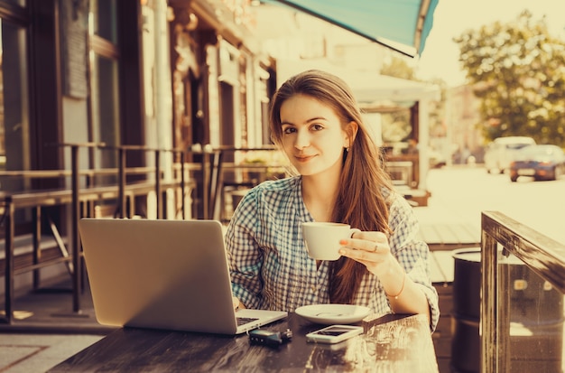 Girl typing on a laptop while holding a cup of coffee