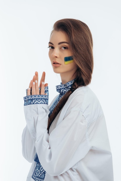 Photo a girl in ukrainian vyshyvanka holds a flag war in ukraine on a white background