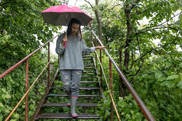 Ragazza sotto un ombrello durante una passeggiata nella foresta primaverile sotto la pioggia