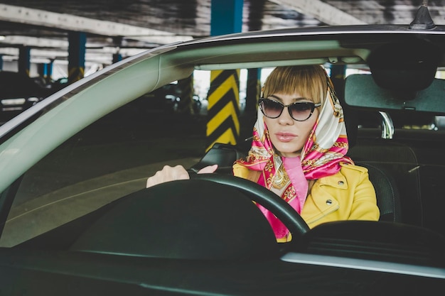 Girl in an underground garage with car Fashionable girl driver stylish rich successful woman in cabriolet