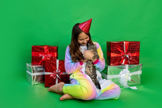 девушка в костюме единорога с подарочными коробками и играет с кошкой