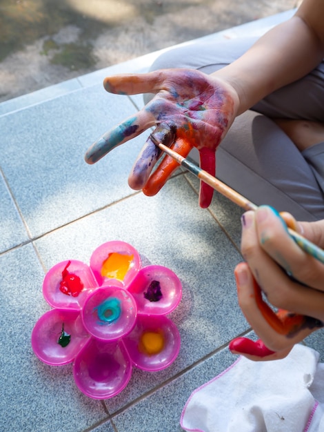 Girl use brush for painting watercolor on fingers