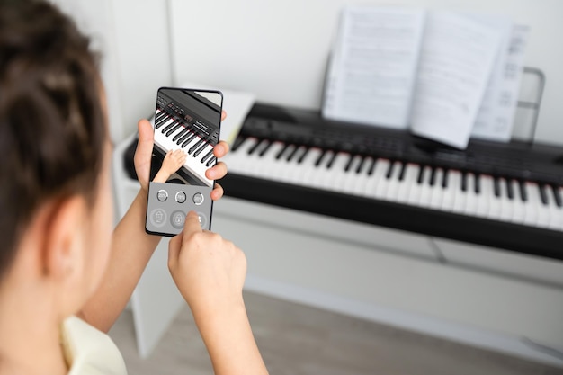 Girl use mobile phone against the background of the piano.