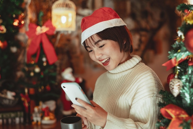 Девушка использует смартфон и наслаждается рождественским праздником, концепцией празднования нового года.