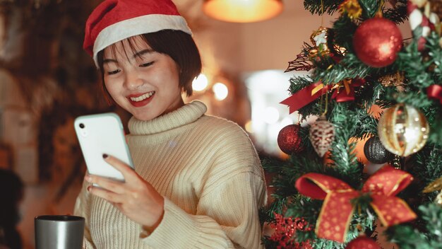 소녀는 스마트폰을 사용하고 크리스마스 휴가, 새해 축하 개념을 즐깁니다.