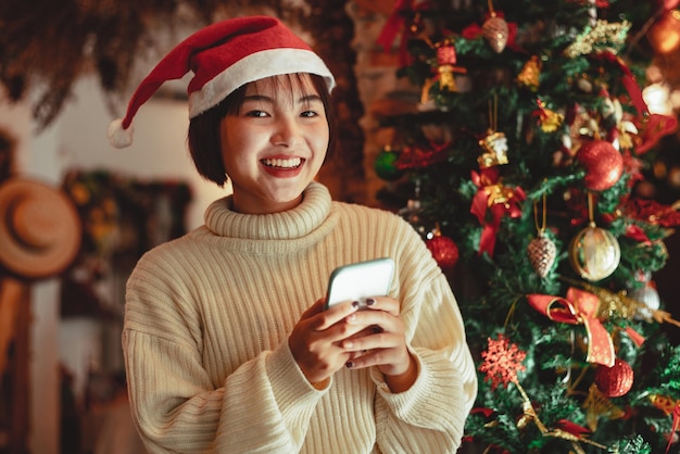 Девушка использует смартфон и наслаждается рождественским праздником, концепцией празднования нового года.