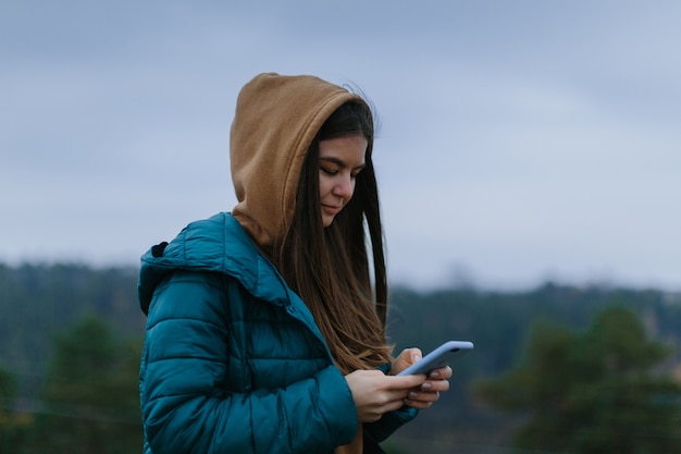 Girl uses the phone while hiking in the mountains