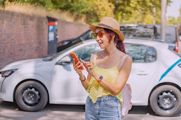 スマートフォンのアプリを使ってカーシェアリングの車を借りたり、タクシーを呼んだりする女の子