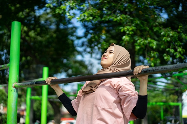 ベールに身を包んだ少女は、公園で手の筋肉を鍛えるために懸垂をします