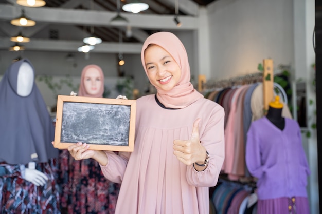 A girl in a veil hold a blackboard with thumbs up while standing