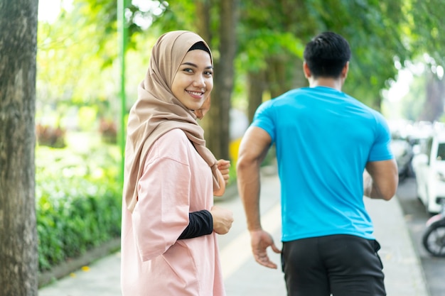 A girl in a veil smile looking at the camera when doing jogging together when outdoor exercise in the park