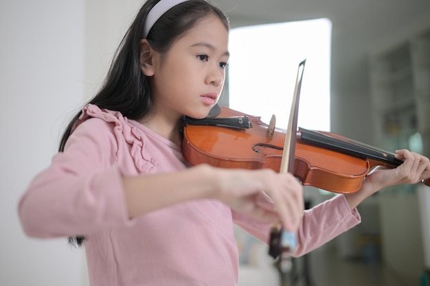 バイオリニストの女の子が家でバイオリンを演奏し練習しています