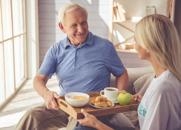 girl volunteer is giving food to old man