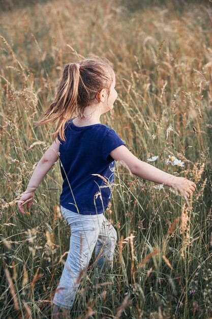 Photo girl walking amidst grassy field