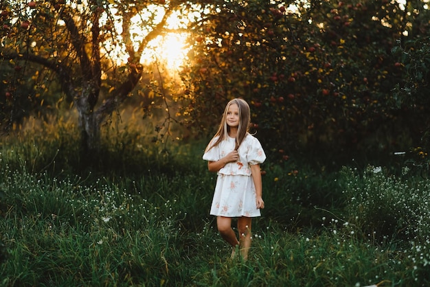 Photo a girl walking in an apple orchard at sunset