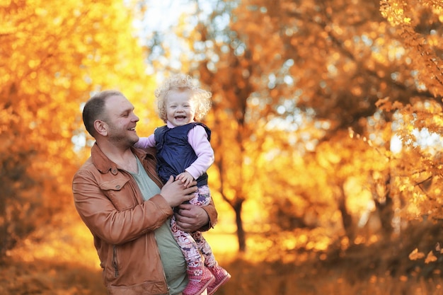 Girl walking in the autumn park. Autumn in the city, girl with dad for a walk. Parents are walking with little children. Autumn park people