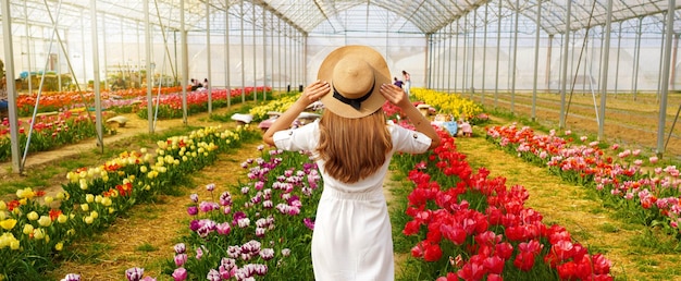 Girl walking between colorful tulips in greenhouse on spring time Banner edition